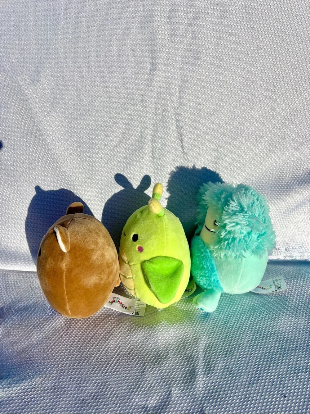 Squishmallows brown Bear, teal Bigfoot, and green grasshopper